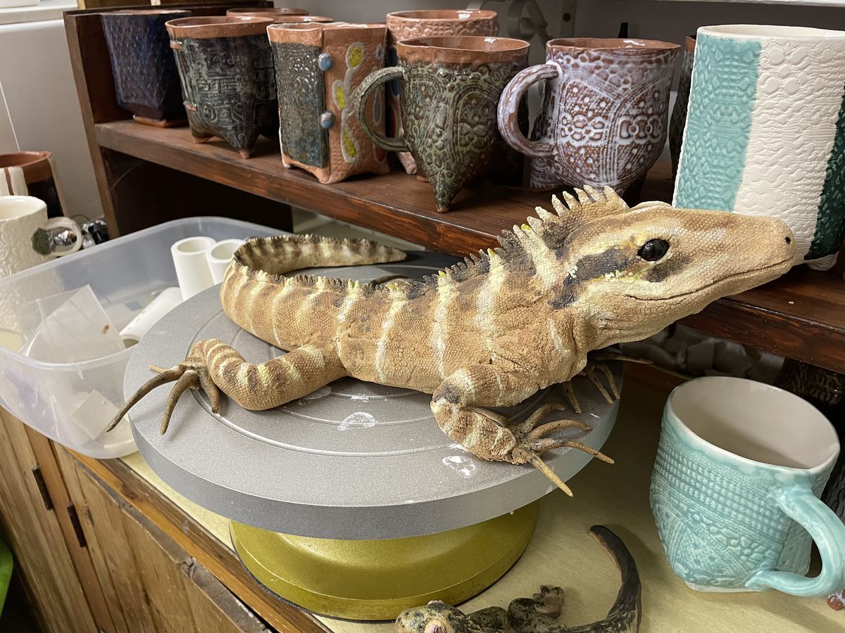 Long ceramic crocodile resting on a banding wheel in the studio