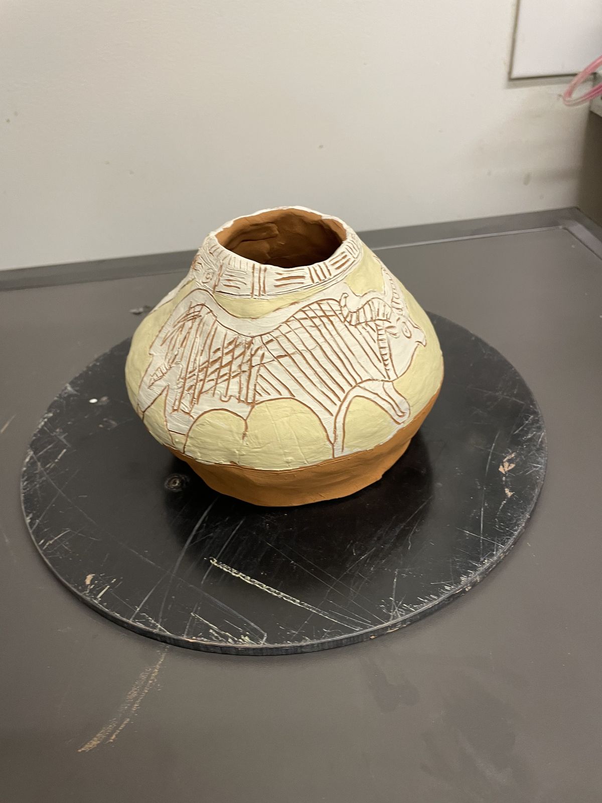 Round-bellied ceramic pot with a lattice of incised lines through white slip