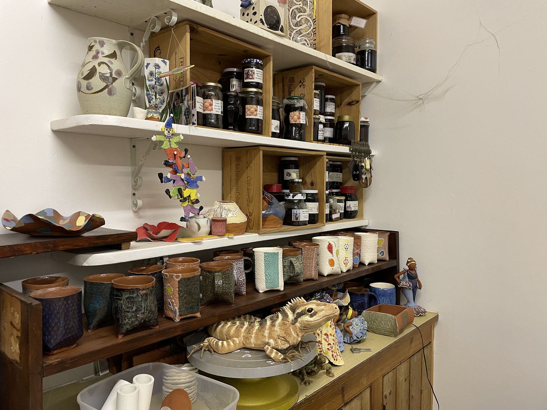Shelves in the studio holding finished pots, tiles, and pieces waiting to be fired