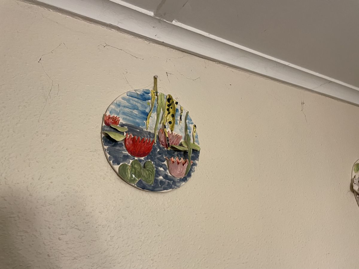 Circular ceramic wall plate painted with a coastal landscape