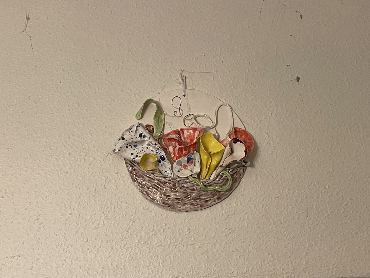 Ceramic wall pocket shaped like a basket filled with flowers