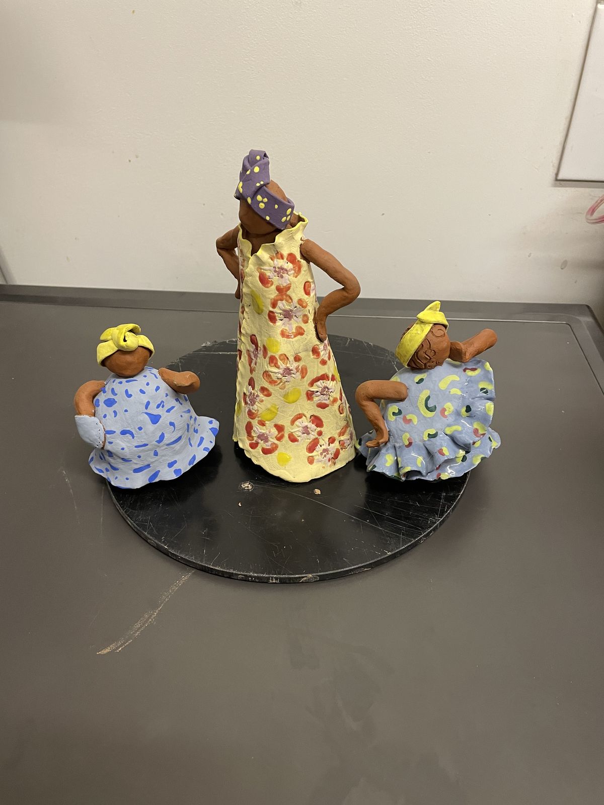 Three hand-built ceramic figures in patterned dresses, grouped together